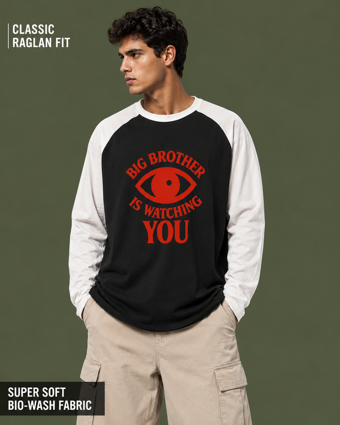A man wearing a black and white raglan long-sleeve shirt with a red graphic that reads 'BIG BROTHER IS WATCHING YOU' and an eye illustration. The background is a solid dark olive green.